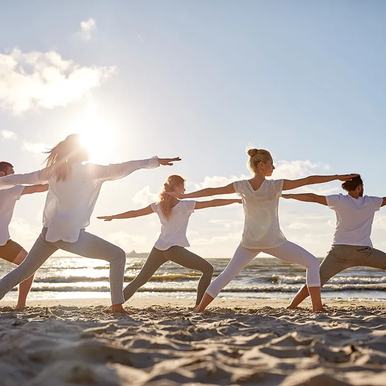 Group enjoying yoga on the beach at sunset